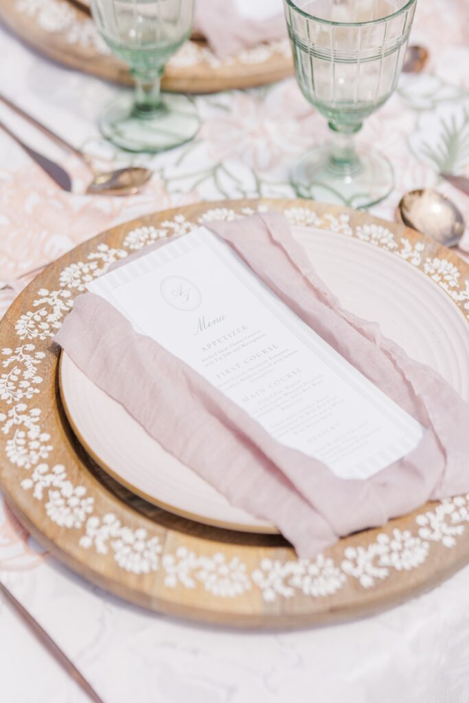 Close-up of wedding place setting with menu card and blush linen napkin at Heritage Museums & Gardens