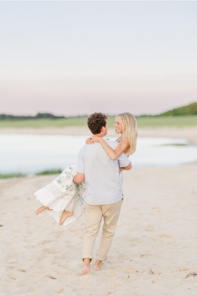 Couple laughing together on a sandy Cape Cod beach at sunset.