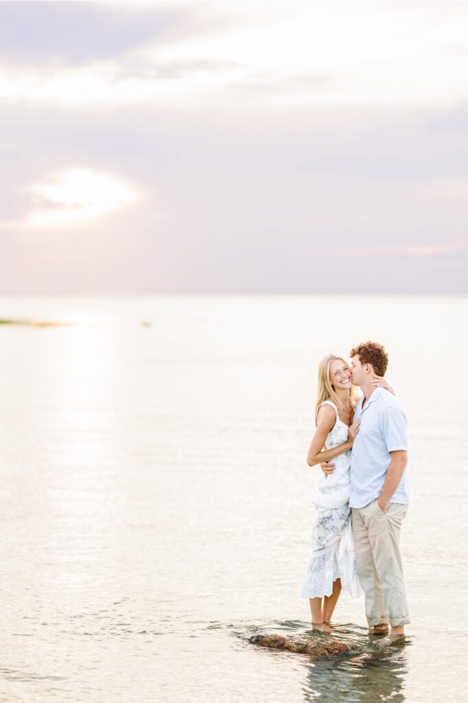Couple embracing along the shoreline during Cape Cod beach engagement photos.