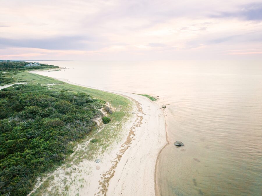 Drone photograph of a quiet Cape Cod beach with dunes and calm shoreline at sunset.