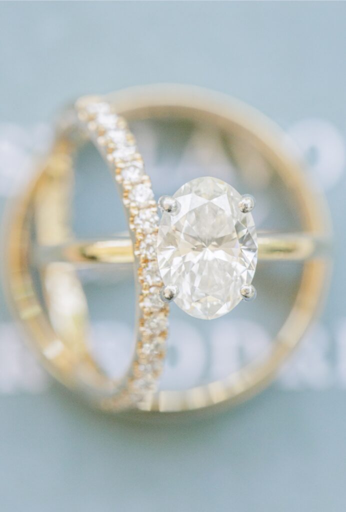 Oval diamond engagement ring and wedding bands photographed in a blue velvet ring box.