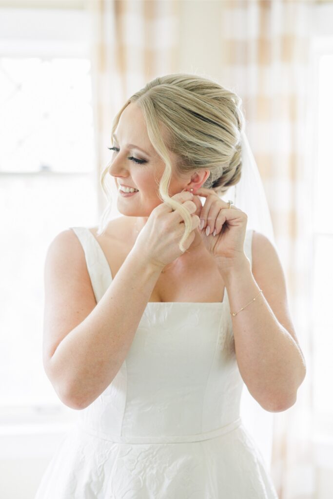 Bride putting on pearl earrings while preparing for her Publick House wedding.