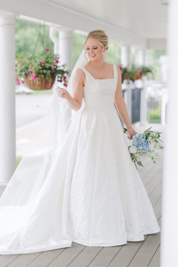 Bride holding her veil and blue hydrangea bouquet during her Publick House wedding.