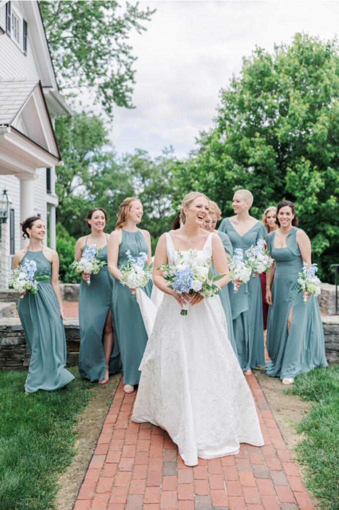 Bride and bridesmaids walk along a brick path during a Publick House wedding.