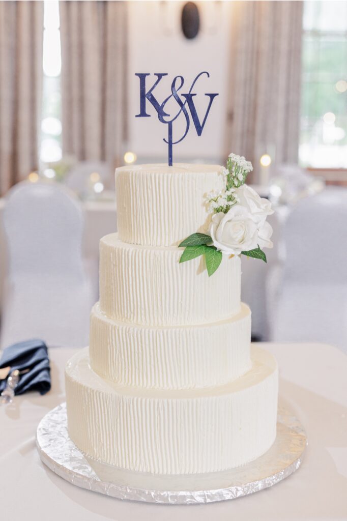 Four-tier white wedding cake with roses and a monogram topper at the Publick House.