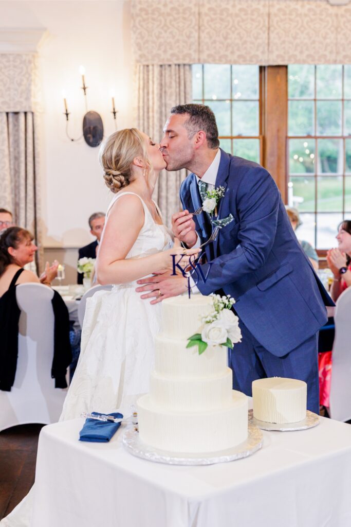 Newlyweds kiss after sharing wedding cake during their Paige Hall reception.