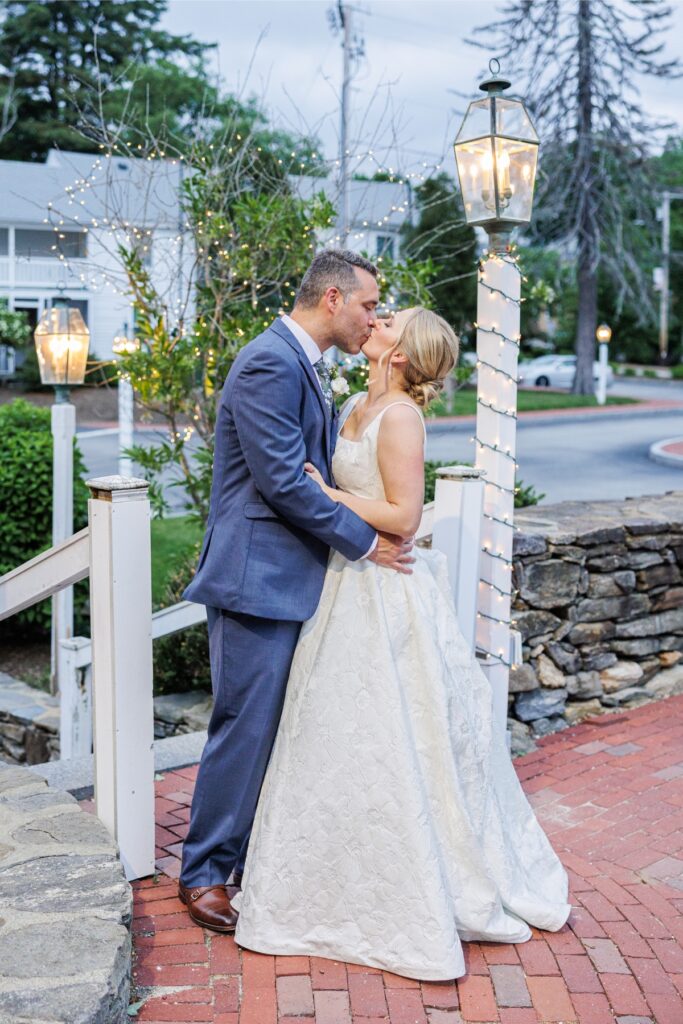 Newlyweds kiss beneath glowing lanterns outside the Publick House Historic Inn.