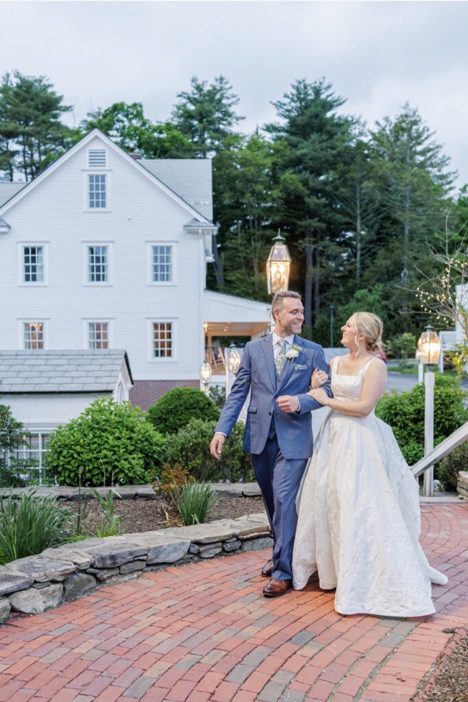 Newlyweds walk beneath glowing lanterns outside the Publick House Historic Inn.