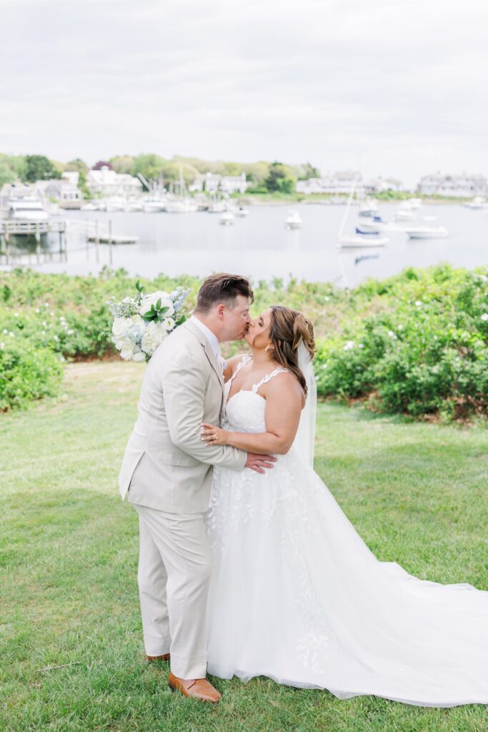 The bride and groom share a kiss after exchanging private vows overlooking Wychmere Harbor. Their waterfront embrace highlights the coastal setting of their Wychmere Beach Club wedding.
