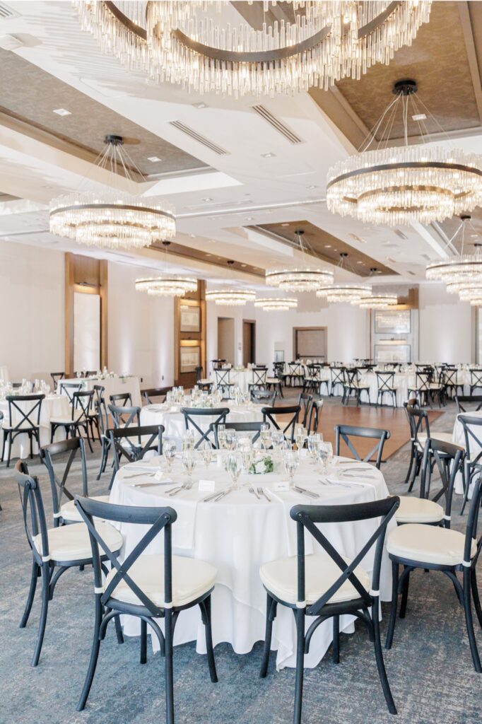 The Artisan Hotel Grand Ballroom arranged with round dinner tables beneath modern chandeliers.