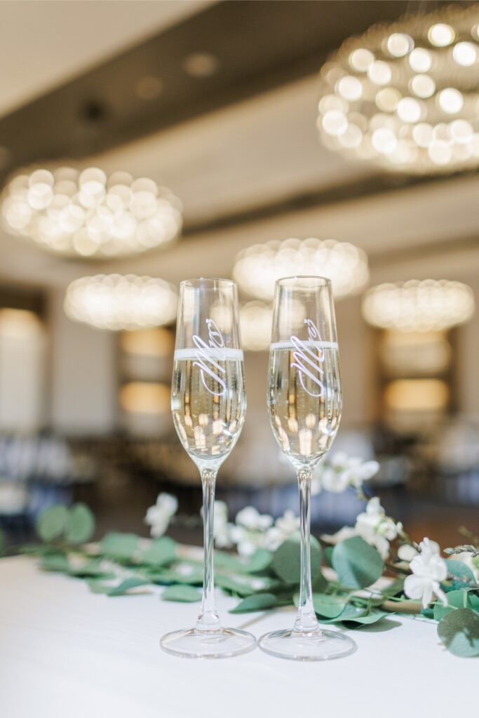 Two champagne flutes displayed with white flowers inside the Artisan Hotel ballroom.