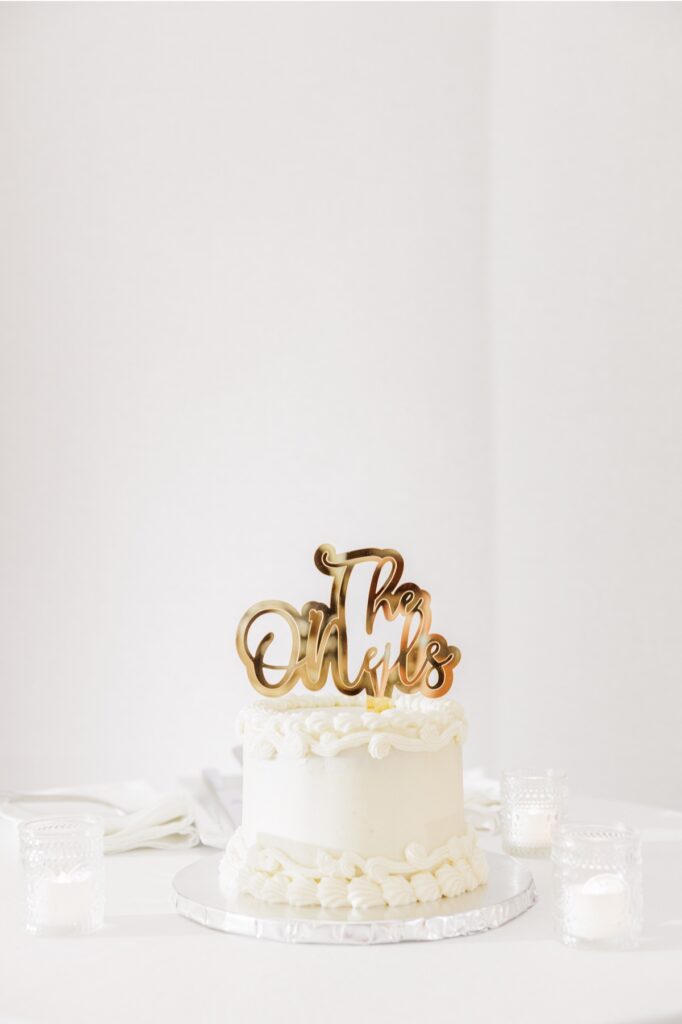 Small white wedding cake topped with a gold Mr. and Mrs. decoration.