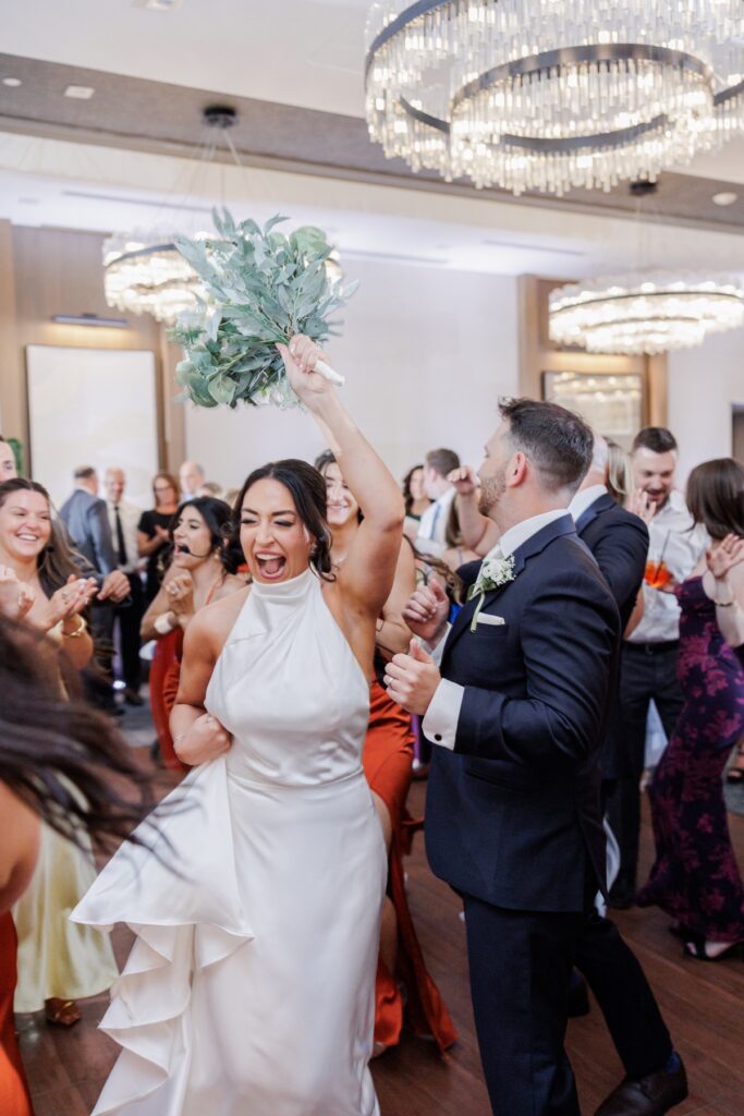 The bride celebrates on the dance floor with the groom and their wedding guests.