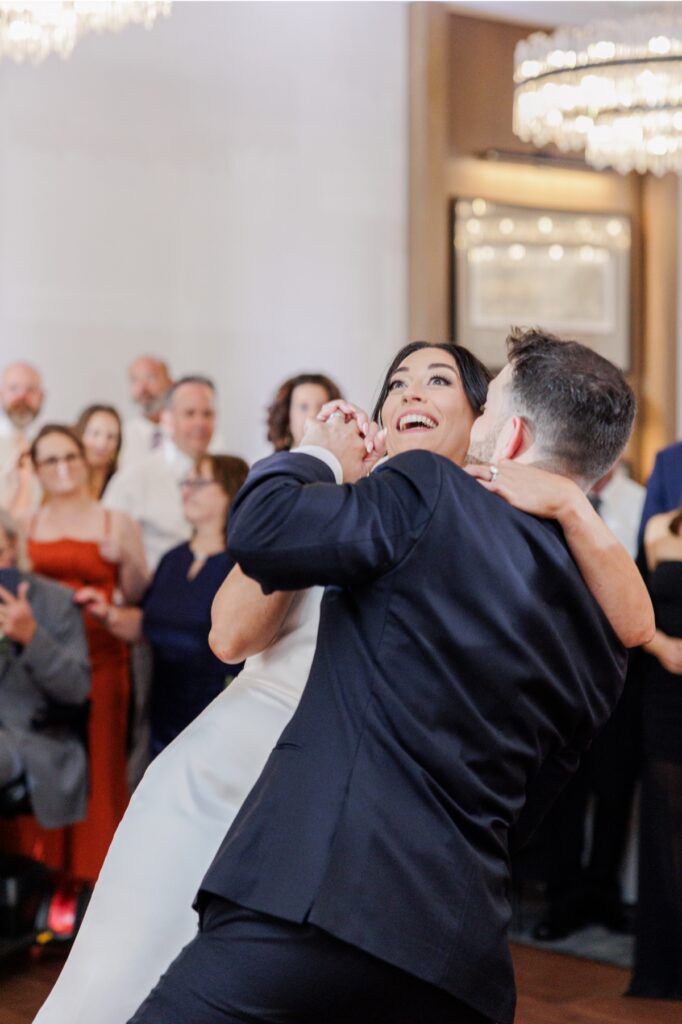 The bride laughs as the groom spins her during their first dance.