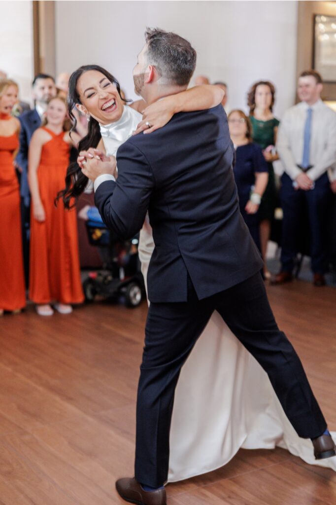 The bride smiles at the groom during their first dance in the Artisan Hotel ballroom.