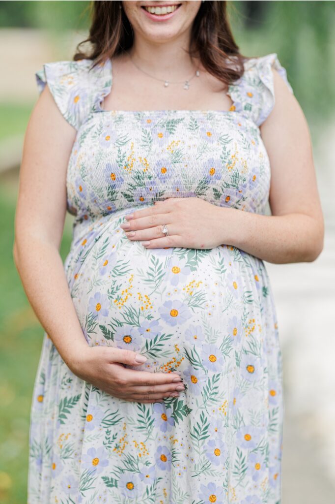 A close up of a pregnant woman's arms holding her pregnant belly.