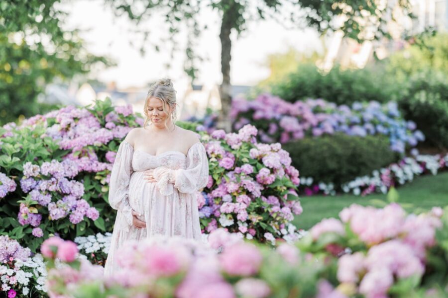 A pregnant woman holding her belly and looking down during her Chatham Bars Inn maternity pictures