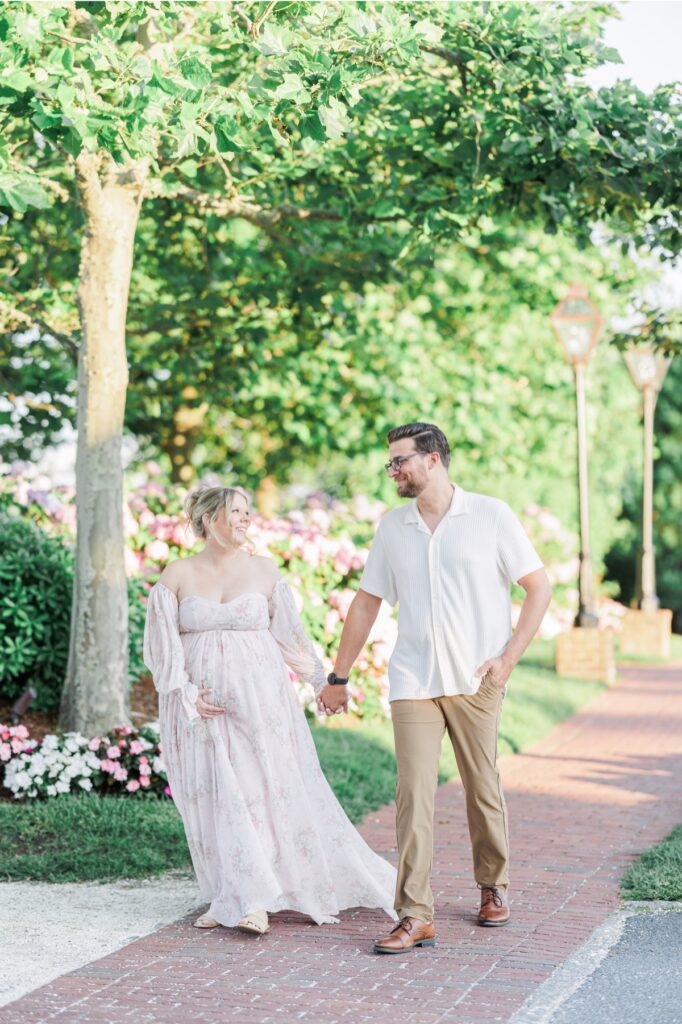 A couple holding hands and walking down the sidewalk during their Chatham Bars Inn maternity photo session.