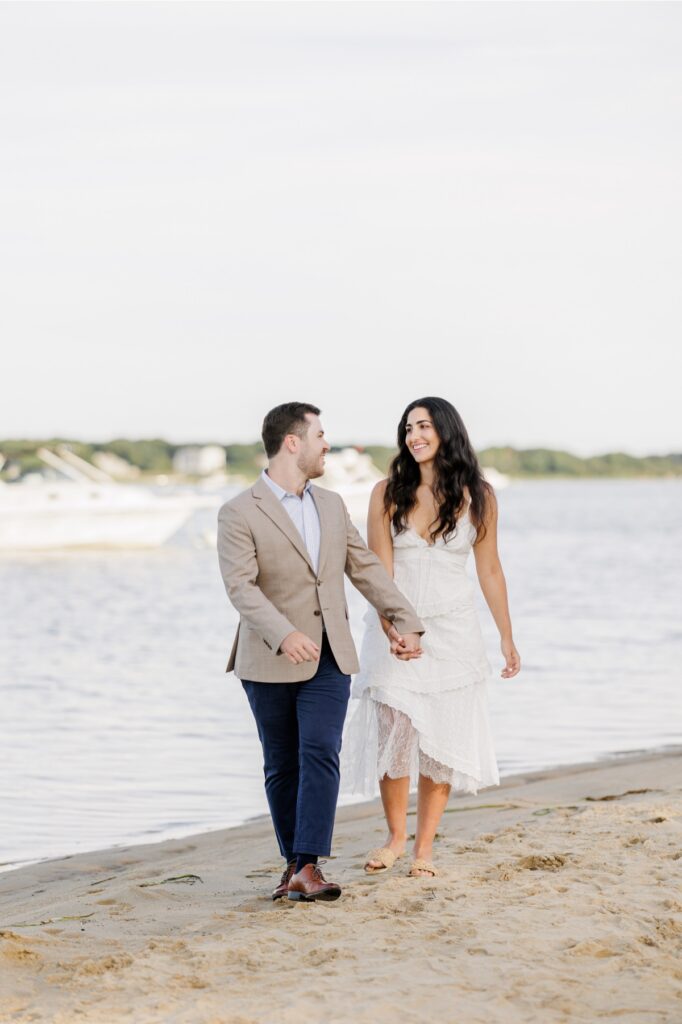 Newly engaged couple walking along a private Falmouth beach during their engagement session.