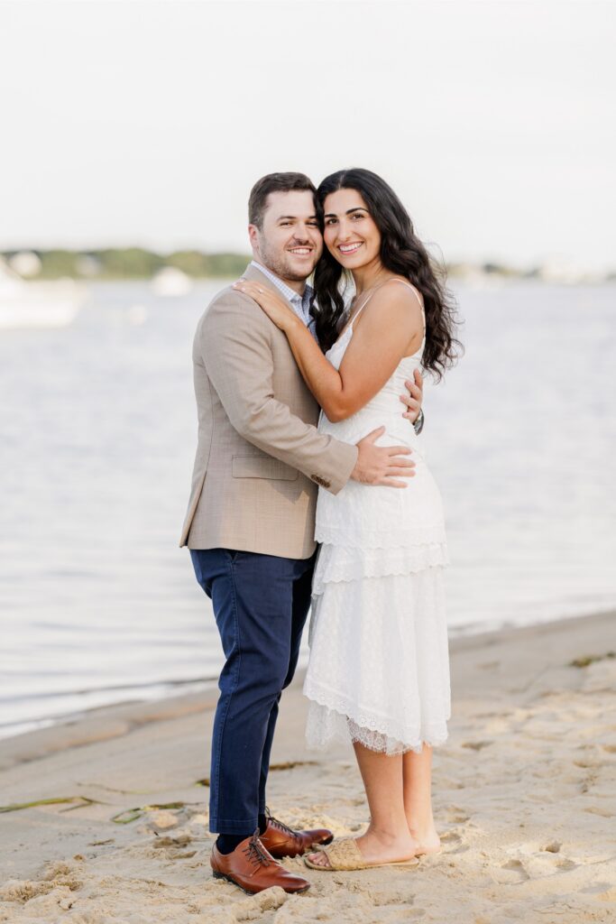 Newly engaged couple smiling together during their Cape Cod beach engagement photos.