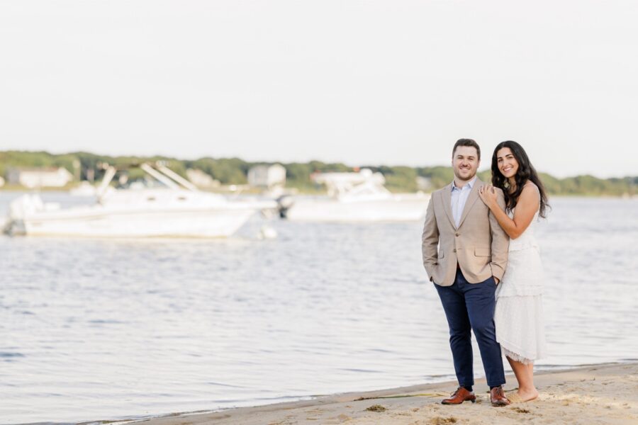 Newly engaged couple posing beside the water during a Falmouth beach engagement session.