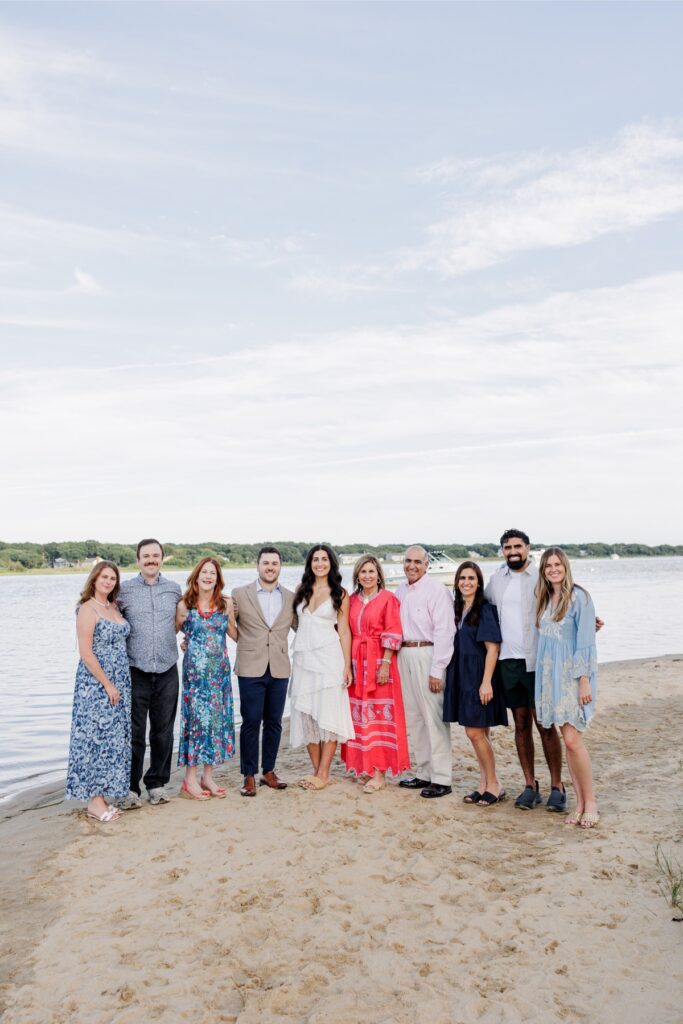 Newly engaged couple posing with family during their private Falmouth beach celebration.