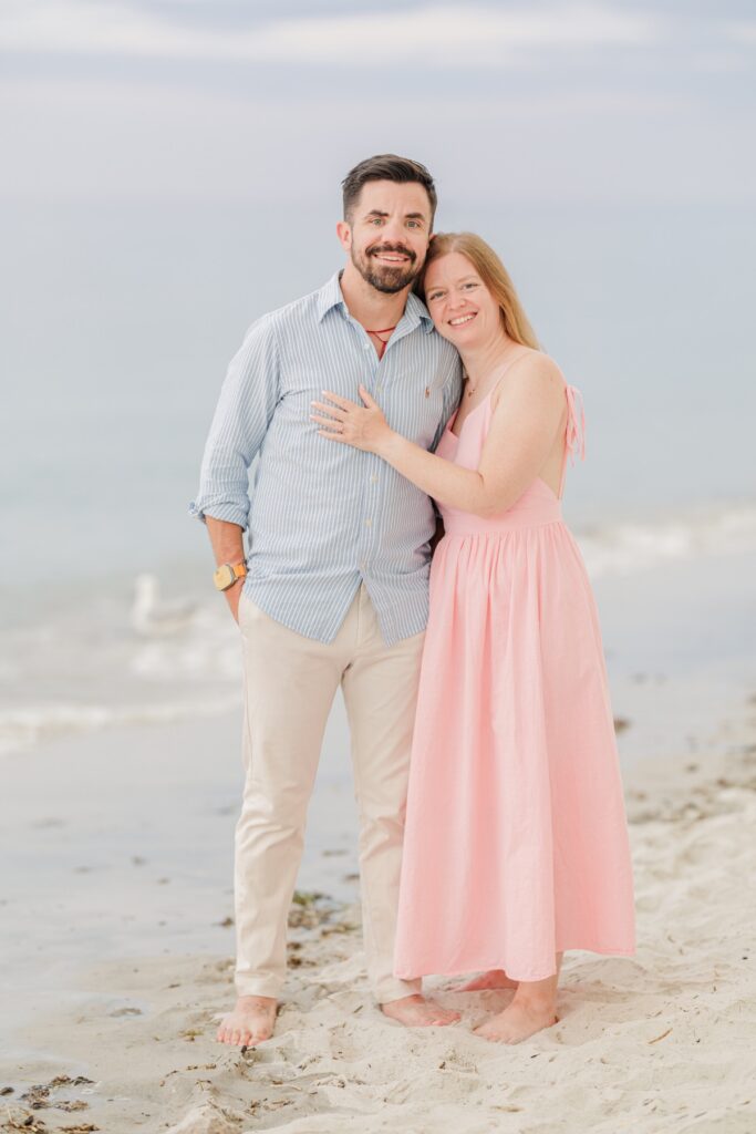 Amy and Joe smile together barefoot beside the water during their Cape Cod engagement session.