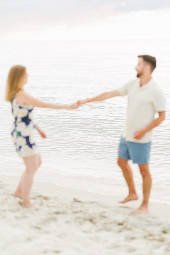 Amy and Joe playfully hold hands beside the water during their Cape Cod beach engagement photos.