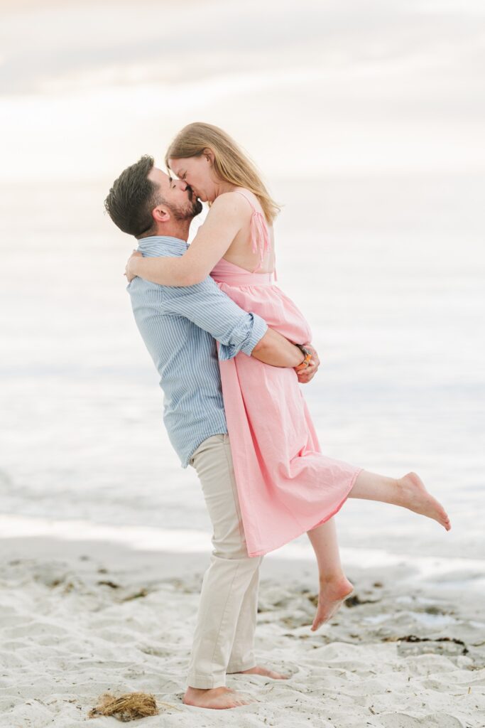 Joe lifts Amy as they touch kiss during their romantic Mayflower Beach engagement photos.