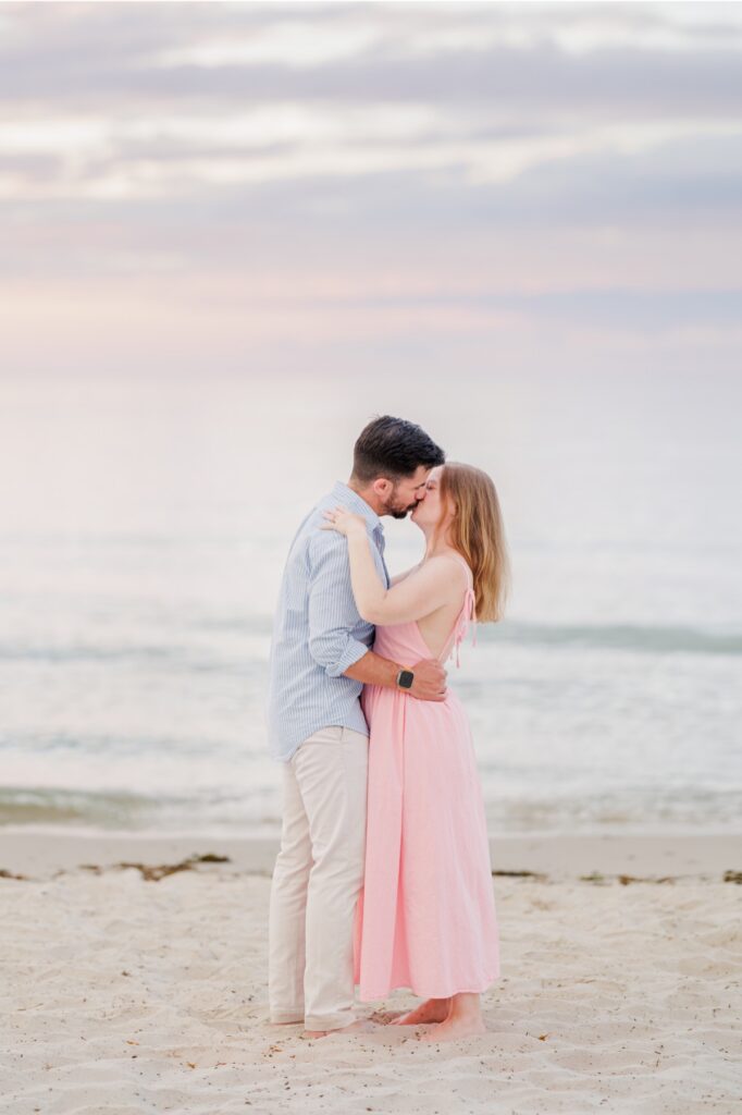 Amy and Joe kiss beside the ocean during their romantic Mayflower Beach engagement photos.