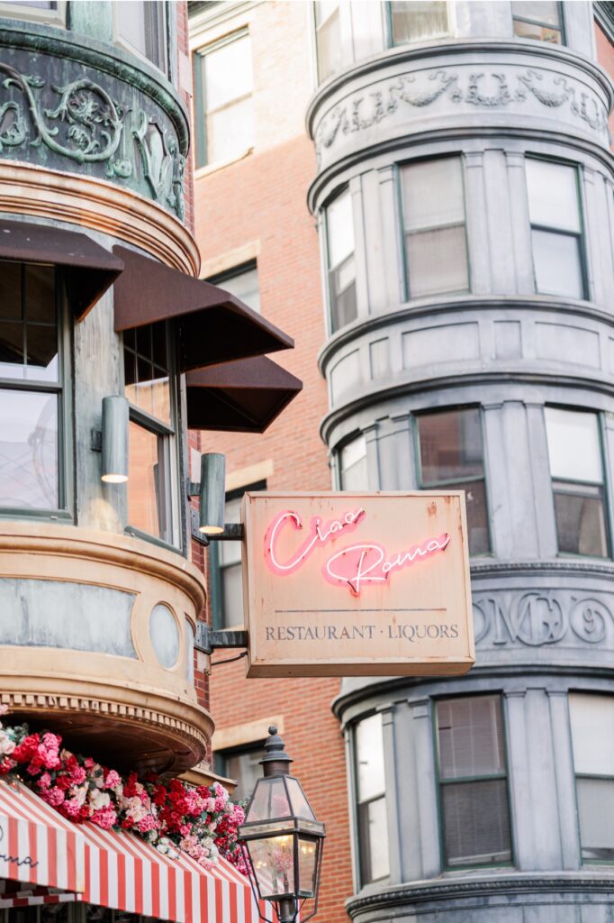 Ciao Roma neon restaurant sign and flower-covered striped awning in Boston’s North End