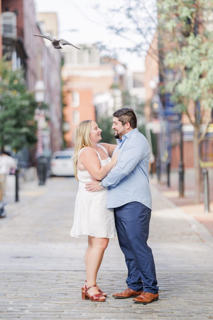 The engaged couple walking hand in hand past Ciao Roma in Boston’s North End