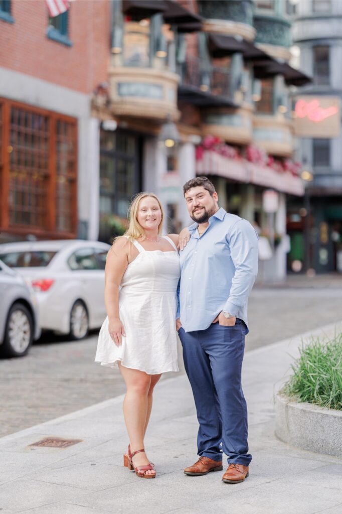 The engaged couple posing with Ciao Roma behind them in Boston’s North End