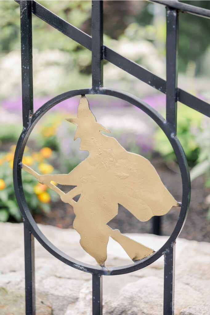 Gold witch emblem on a black iron gate at the Salem Country Club wedding venue in Peabody.