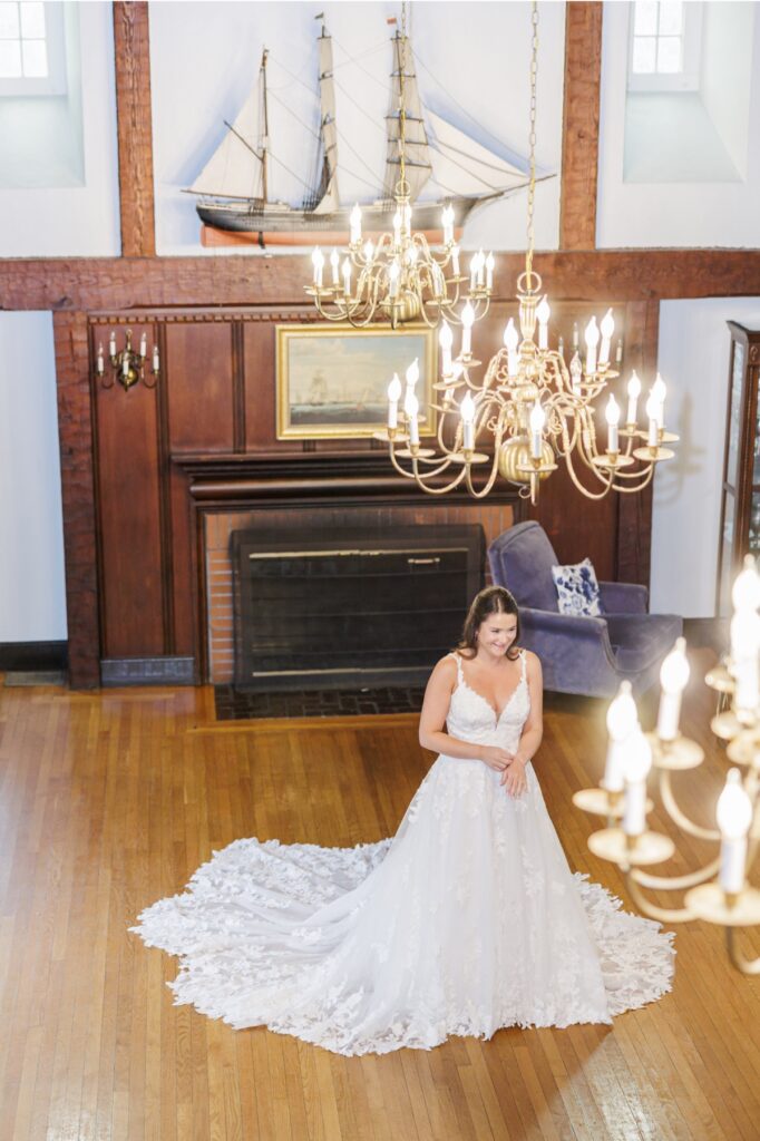 The bride beneath glowing brass chandeliers in the nautical room at her Salem Country Club wedding.