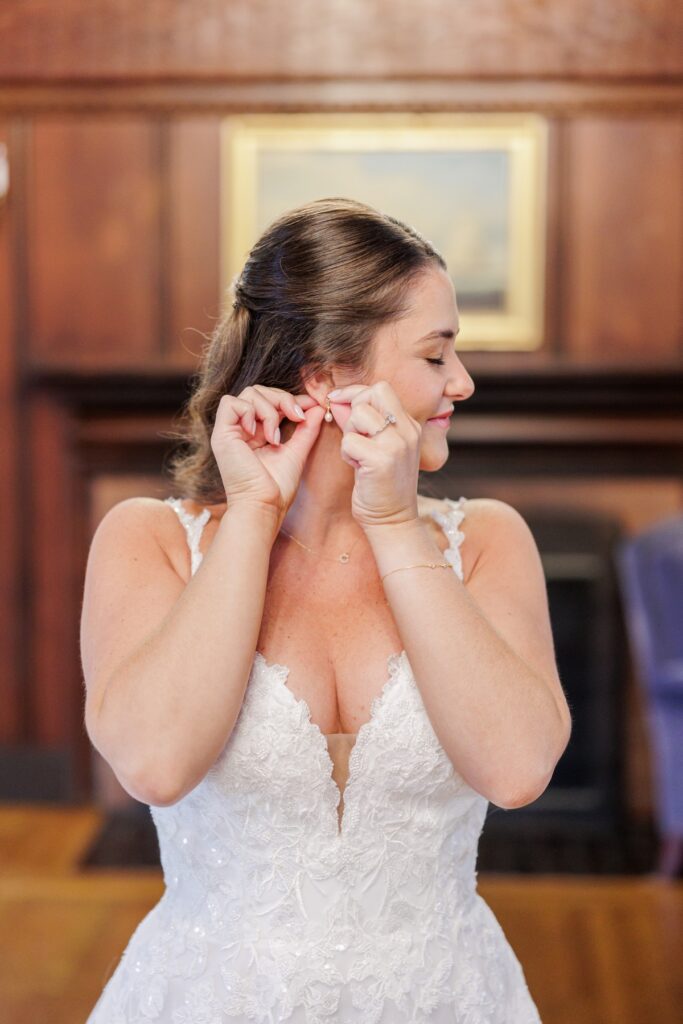 The bride putting on a drop earring while getting ready for her Salem Country Club wedding.