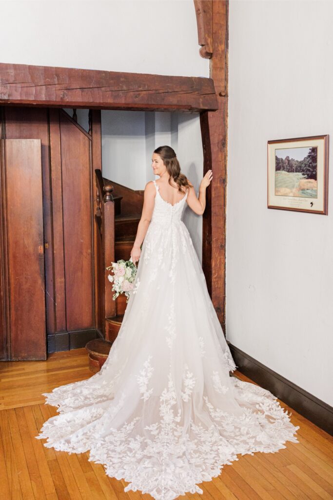 The bride holding her bouquet beside a wooden staircase at her Salem Country Club wedding.