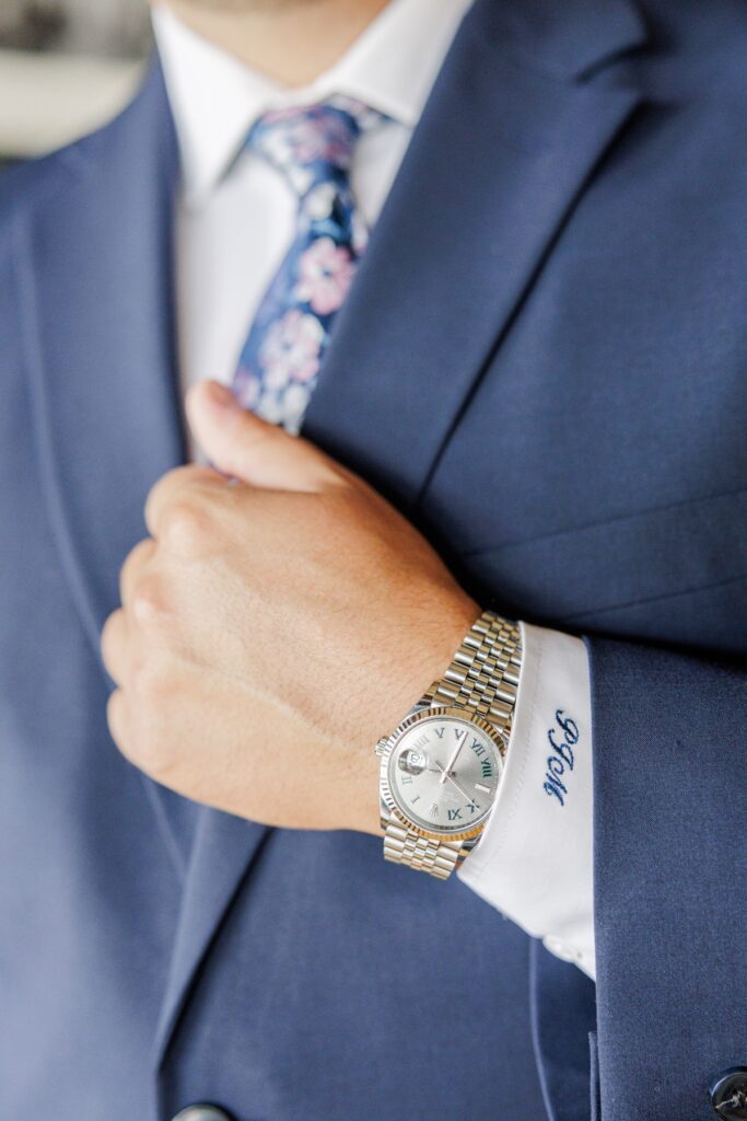 The groom’s wristwatch and embroidered shirt cuff against his navy Salem Country Club wedding suit.
