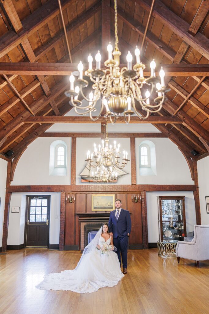 The bride and groom framed by vaulted wood beams and brass chandeliers at their Salem Country Club wedding.