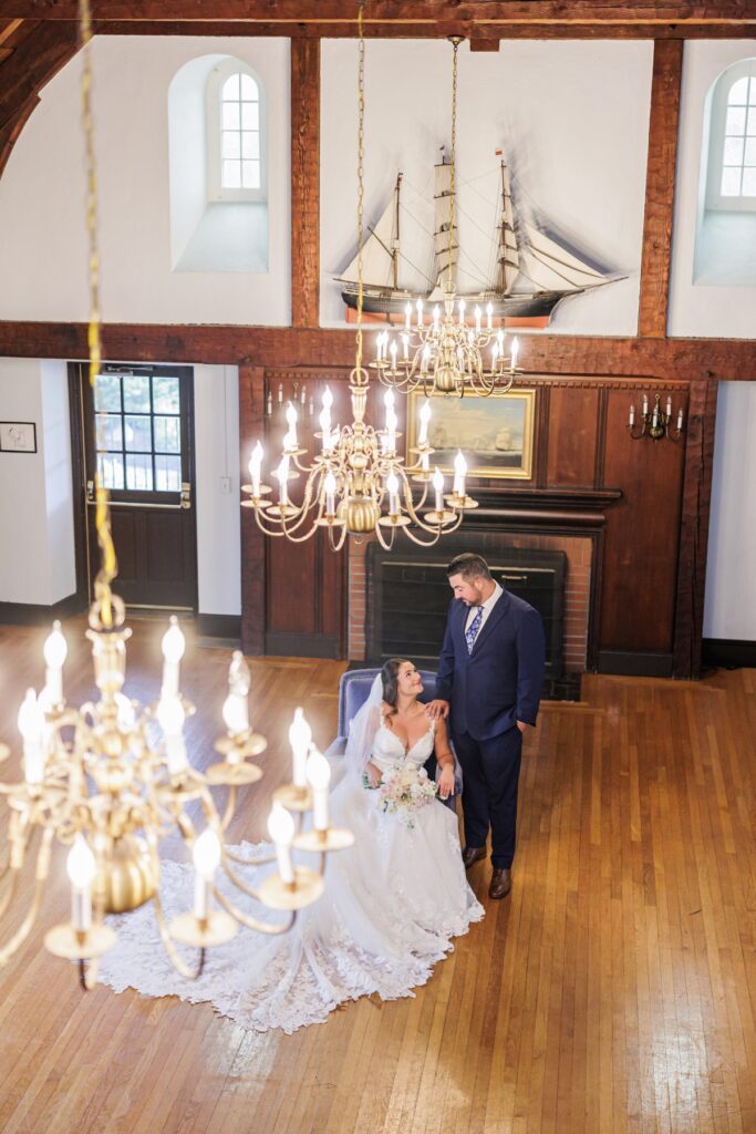 Overhead view of the seated bride looking up at the groom beneath Salem Country Club wedding chandeliers.