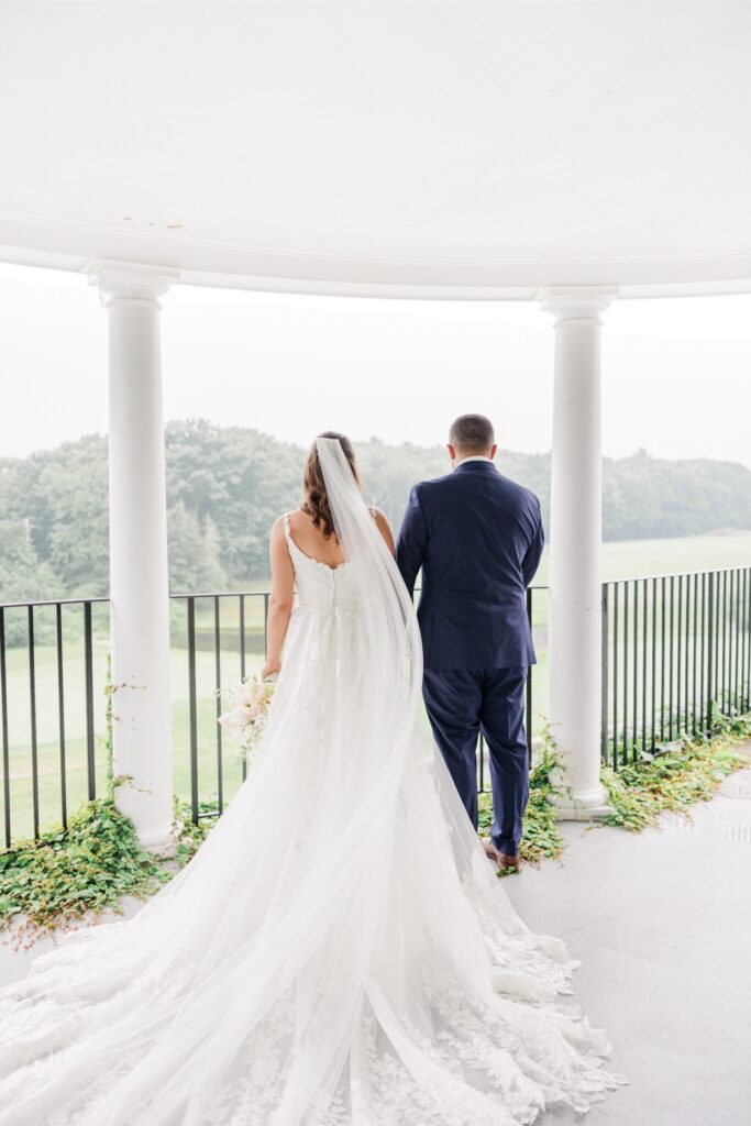 The bride and groom looking over the golf course from the covered porch at their Salem Country Club wedding.