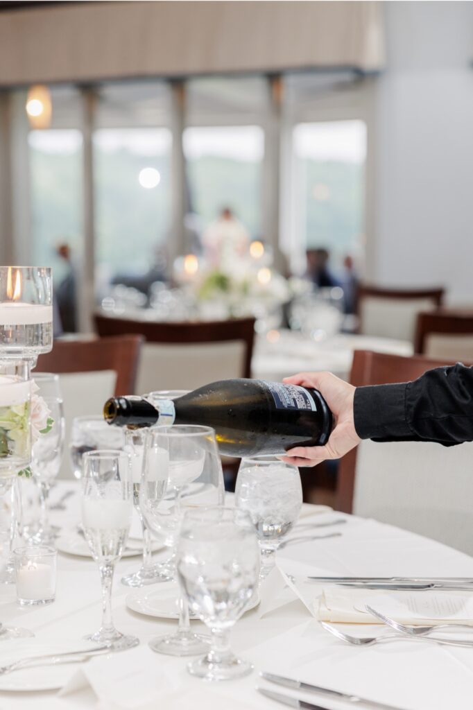 A server pouring wine beside candlelit place settings at the Salem Country Club wedding reception.