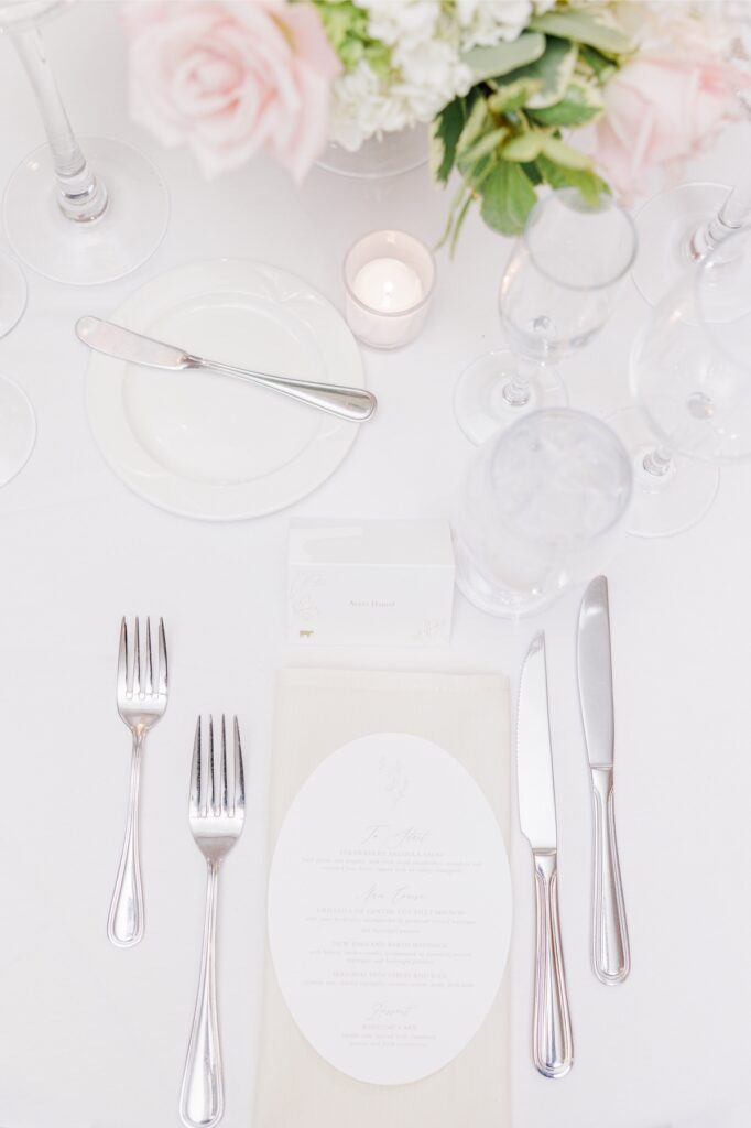 White linen place setting with silverware, glassware, and a place card at the Salem Country Club wedding reception.