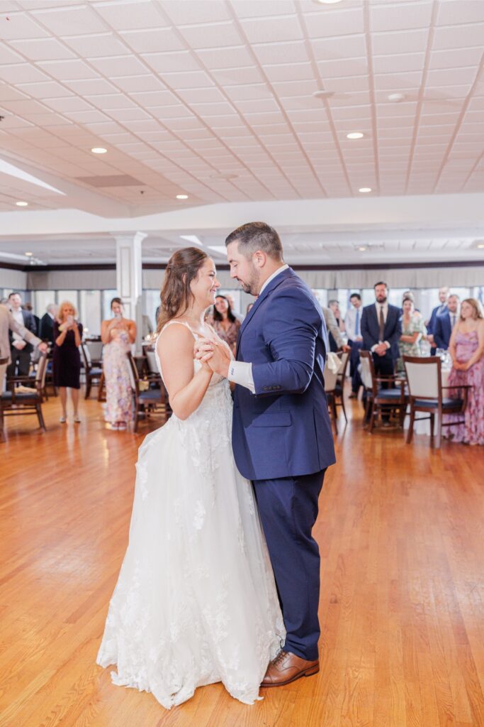 The bride and groom smiling during their first dance as guests watch at the Salem Country Club wedding reception.