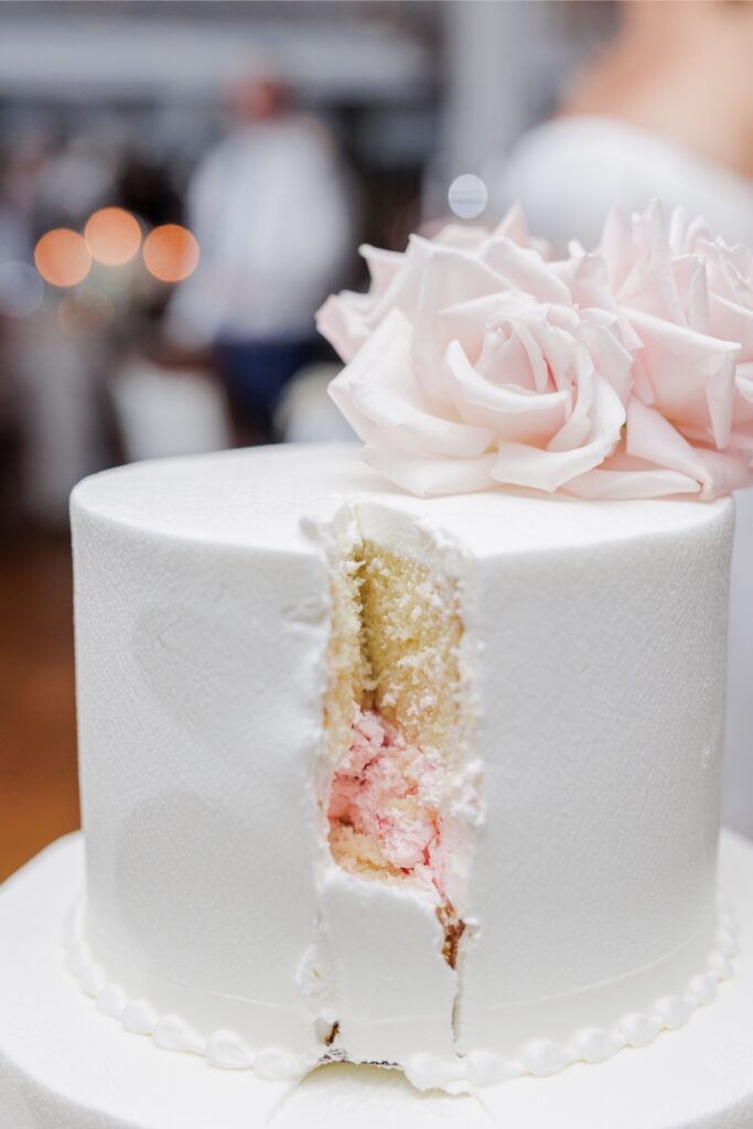 Cut Salem Country Club wedding cake revealing golden cake layers and pink filling beneath white frosting.