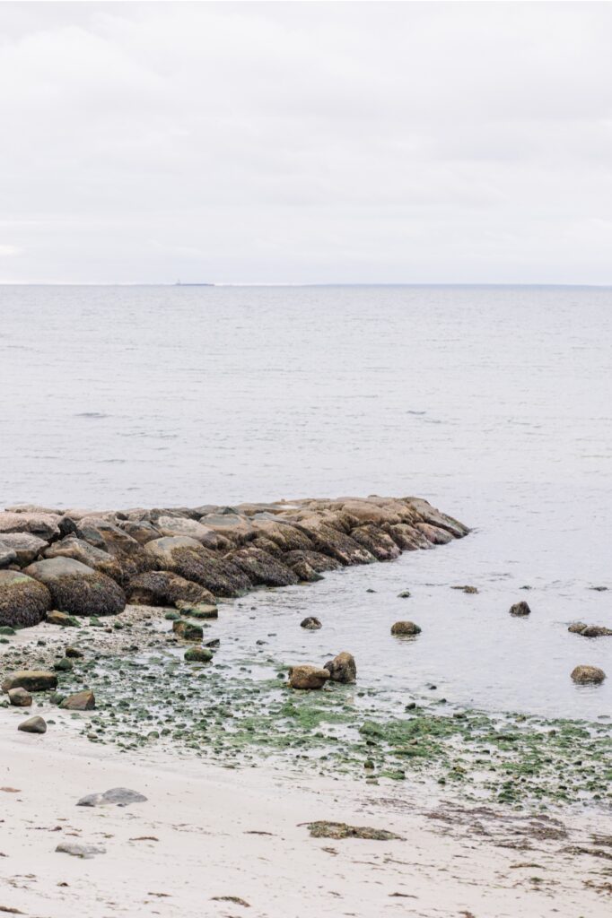 Rock jetty extending into calm water at Old Silver Beach on Cape Cod.