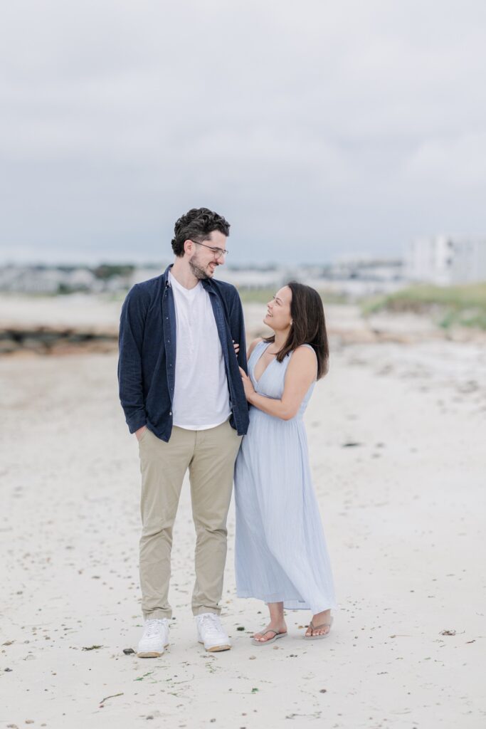 Couple smiling at each other during Cape Cod engagement photos on the beach.