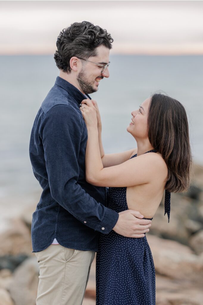 Woman smiling up at her fiancé while holding his shirt collar.