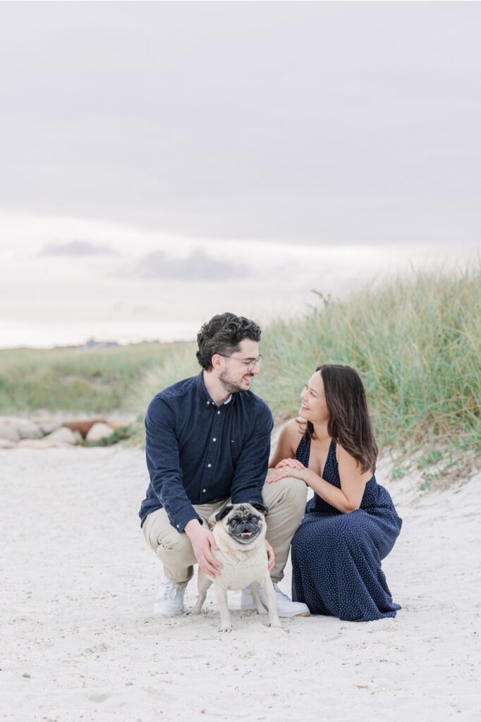 Couple sitting beside dune grass during Cape Cod engagement photos.