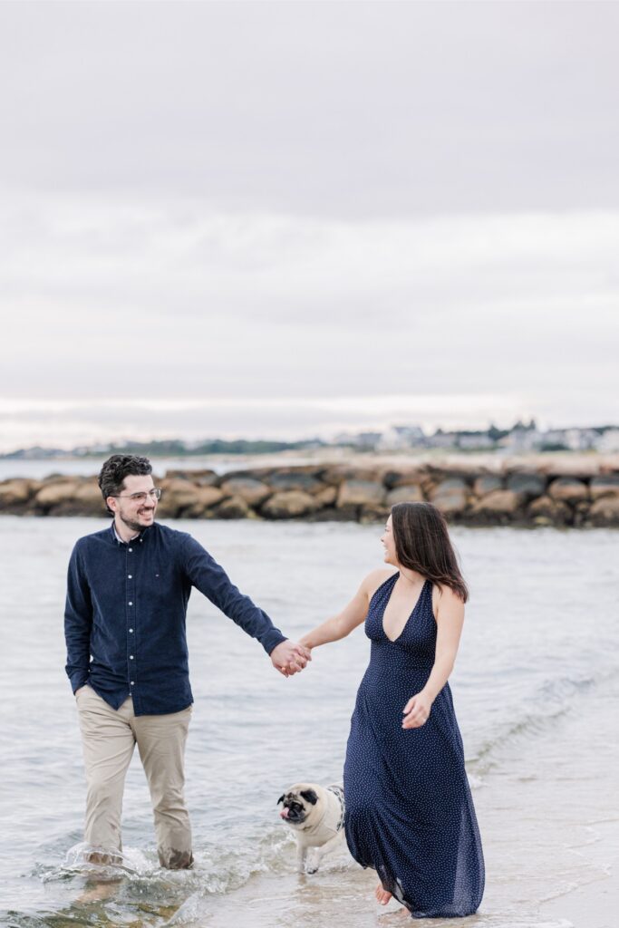 Couple smiling at each other and holding hands by the water.